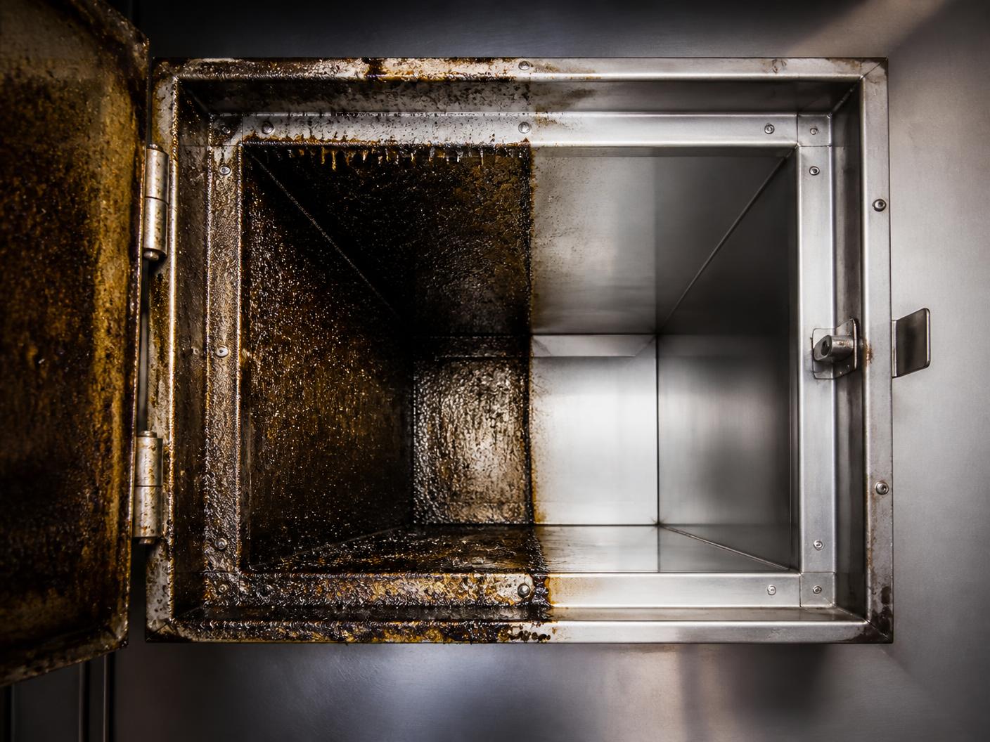 Exhaust duct access panel showing grease buildup on one side and clean metal on the other